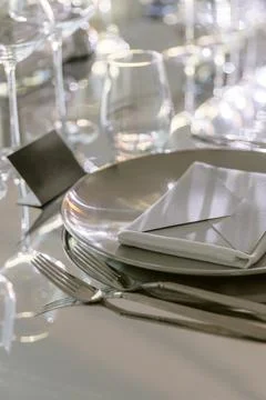 Elegant restaurant table setting with plates and crystal glasses in soft ligh Stock Photos