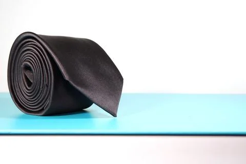 Elegant solid black color polyester fabric necktie rolled over white background Foto stock