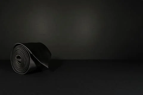 Elegant solid black color polyester fabric necktie rolled over white background Foto stock