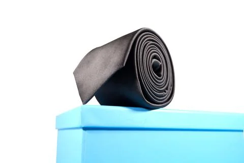 Elegant solid black color polyester fabric necktie rolled over white background Stock Photos