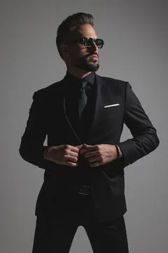 Elegant stylish man buttoning jacket and looking away Stock Photos