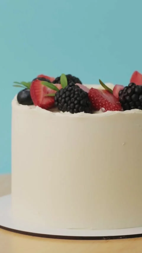 Elegant summer cake with red and black berries rotating on the blue background Stock Footage 314103100