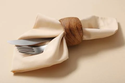 Elegant table setting with beige napkin, wooden ring, silver fork, and knife  Stock Photos