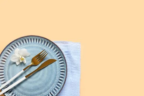 Elegant table setting with a blue ceramic plate golden fork and knife white o Stock Photos