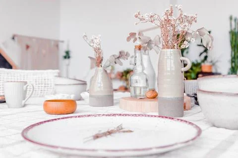 Elegant table setting featuring ceramic vases with dried flowers, glass bottles Stock Photos