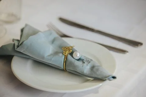 Elegant table setting featuring a folded blue napkin with a gold napkin rin.. Stock Photos