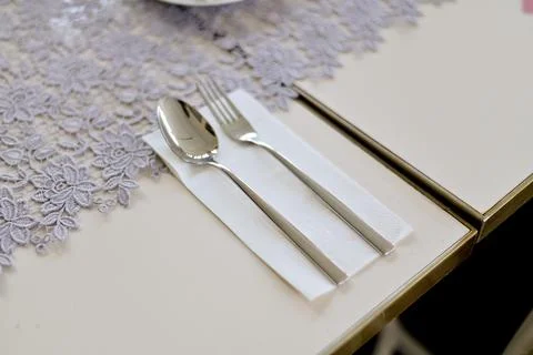 Elegant table setting featuring a shiny silver spoon and fork placed neatly.. Stock Photos