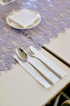 Elegant table setting featuring a shiny silver spoon and fork placed neatly.. Stock Photos