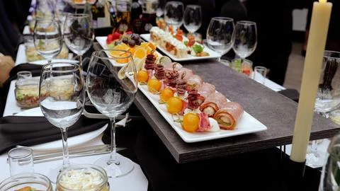 Elegant table setting featuring stemmed wine glasses, gourmet canapes, meat Stock Photos