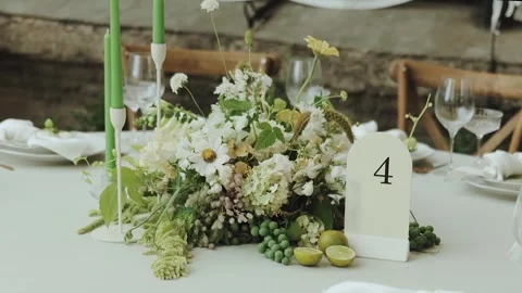 Elegant Table Setting featuring a Stunning Floral Centerpiece and Soft Candle Stock Footage 308398139