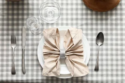 Elegant table setting with folded napkin and silverware on gingham tablecloth Stock Photos