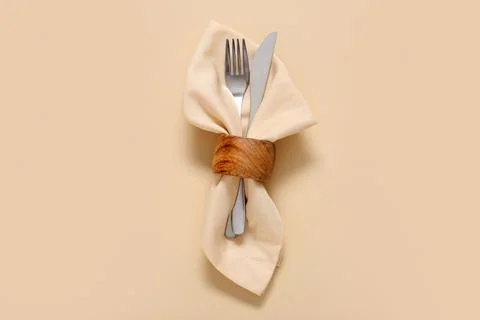 Elegant table setting with fork and knife in beige napkin ring on neutral bac Stock Photos