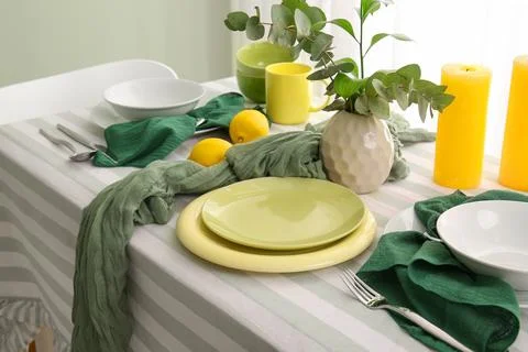 Elegant table setting with green and yellow dinnerware, eucalyptus, lemons, a Stock-Fotos