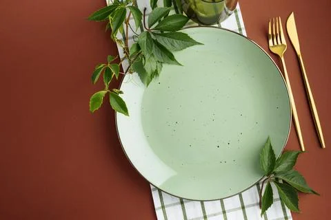 Elegant Table Setting With Green Plate And Gold Cutlery Decorated With Ivy .. Stock Photos