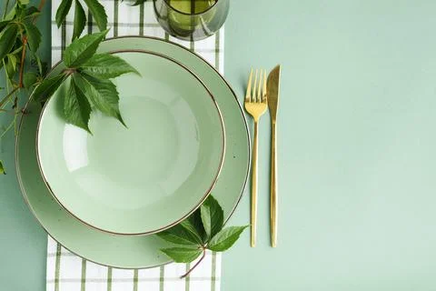 Elegant table setting with green plates and golden cutlery and fresh green .. Stock Photos