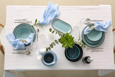 Elegant table setting with light blue ceramic plates, Silverware, and green e Stock Photos