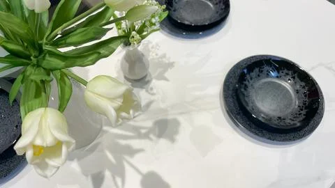 Elegant table setting with modern black plates and fresh white tulips casti.. Foto stock