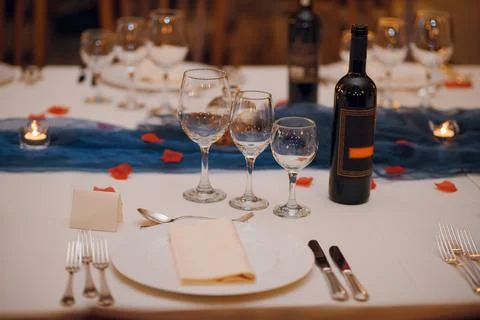 Elegant table setting with wine glasses, rose petals, and candlelight for a.. Stock Photos