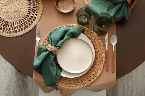 Elegant table setting with a woven placemat, ceramic plates, green napkin, an Stock Photos