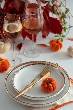 Elegant Thanksgiving Table Setting with Pumpkins Wine Glasses and Golden Cu.. Stock Photos