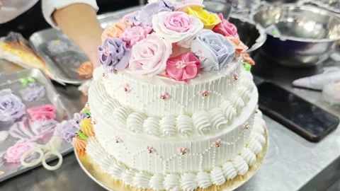 Elegant two-tiered wedding cake decorated with colorful buttercream roses. Vídeo Stock 344746536