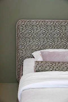 Elegant upholstered designer bed with patterned headboard Stock Photos