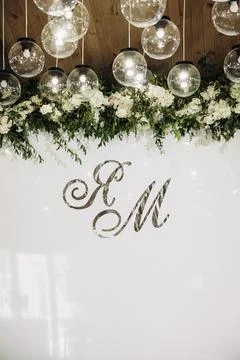 This elegant wedding backdrop features initials, vibrant flowers, and decorat Stock Photos