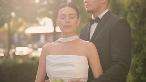 Elegant wedding couple posing in a garden at sunset Stock Footage 343910357