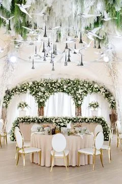 Elegant wedding reception hall featuring round tables, white and gold chair.. Stock Photos
