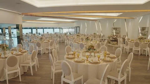 Elegant Wedding Reception Hall with Round Tables White Chairs and Gold Glassware 库存影片 332920899
