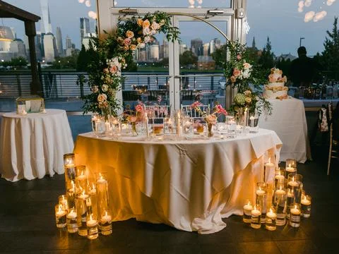 Elegant wedding reception setup featuring floral decor, candlelight, and a city Stock Photos