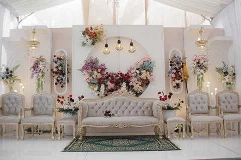Elegant wedding reception stage setup with floral arch and tufted seating Stock Photos