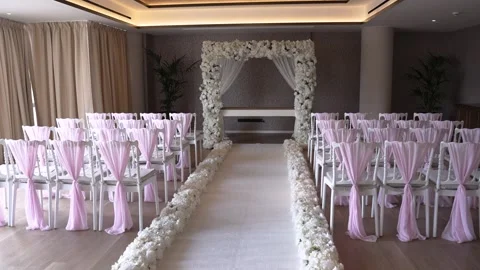 Elegant wedding setup in a spacious hall with floral decorations and chairs Stock Footage 335263049