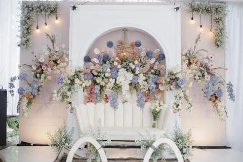 Elegant wedding stage backdrop featuring white couch and abundant pastel flowers Stock Photos
