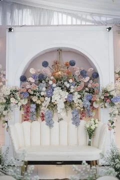 Elegant wedding stage decor featuring a white sofa and lush floral arrangements Stock Photos