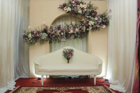 Elegant wedding stage setup featuring a white sofa and abundant floral decor Stock Photos