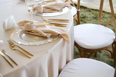 Elegant wedding table setting with soft beige linens, gold cutlery, and Stock Photos