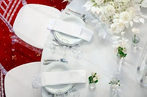 Elegant wedding table setting with white flowers and glassware on red carpet Stock Photos