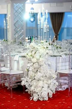 Elegant wedding table setting with white floral arrangement and glassware Stock Photos