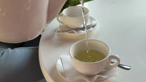 Elegant white tea set on table with white tablecloth in cozy outdoor cafe Stock Footage 345736893