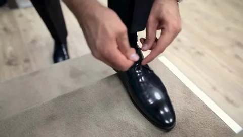 An elegantly dressed man puts on and ties the laces on black patent leather.. Stock Footage 265942604