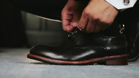 An elegantly dressed man ties his shoes. Stock Footage 295334804