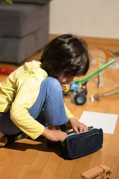 Elementary age boy playing on floor with toys and pencil case Stock Photos