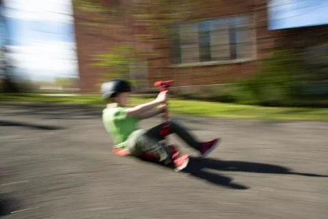 Elementary aged boy in motion riding scooter on pavement outdoors Fotos Stock