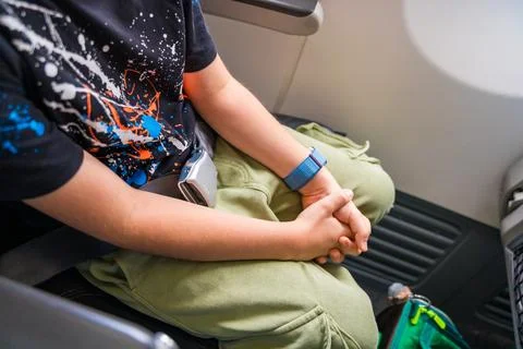 Elementary boy has fastened his seatbelt on the plane and is waiting for takeoff Stock Photos