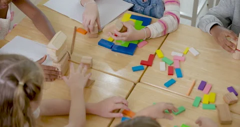 Elementary children place colorful blocks into pattern on wooden desk during Stock Footage 335459895
