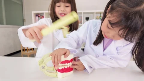 Elementary Girls in Lab Coats Learning Dental Hygiene with Tooth Model Stock Footage 340183121