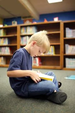 Elementary School Aged Child Reading Book at Library Stock Photos