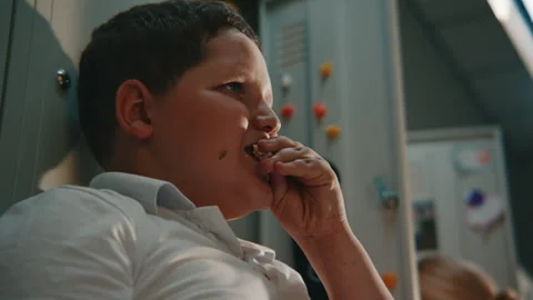 Elementary School Boy Eating Homemade Sandwich beside Locker During Typical Stock Footage 342038221