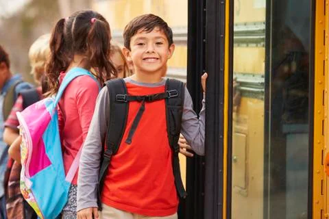 Elementary school boy at the front of the school bus queue Stock Photos